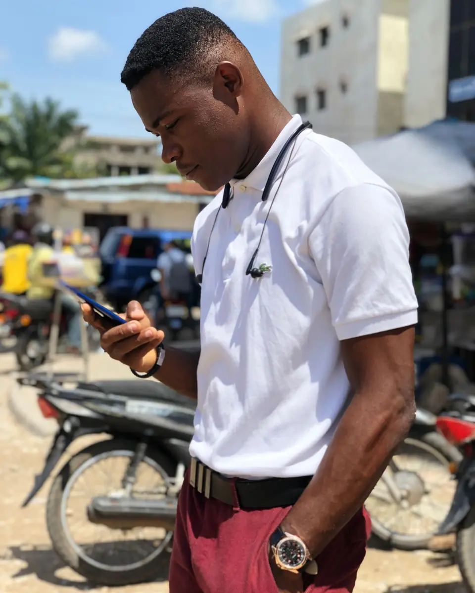 Un jeune homme consulte son téléphone dans une rue animée.