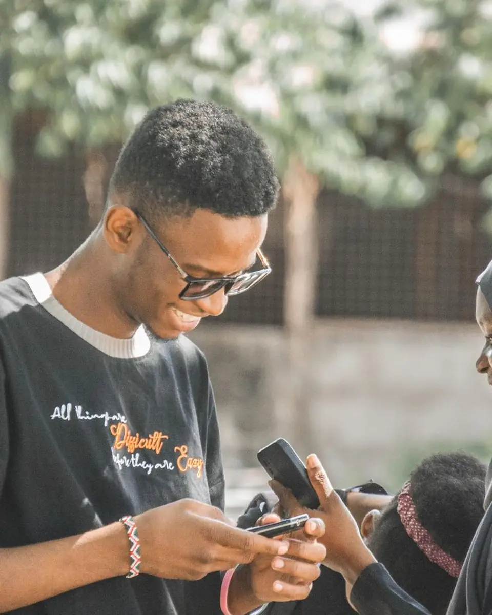 Des jeunes regardent leur téléphone dans la rue.