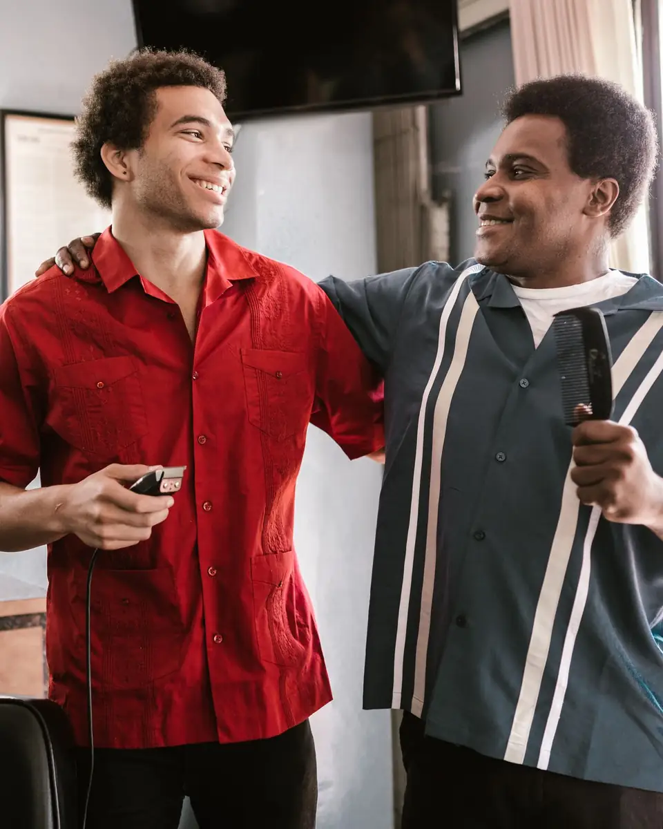Deux jeunes coiffeurs sourient dans leur salon.